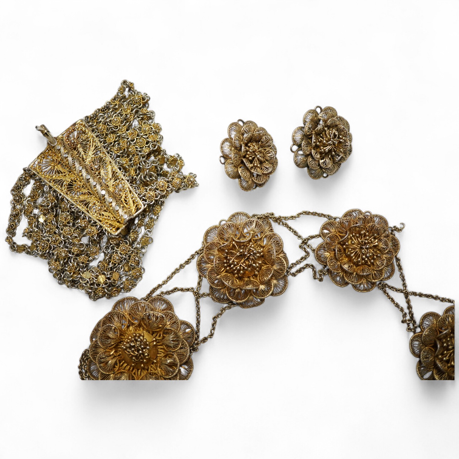 A gilt white metal filigree parure, comprising a necklace, 36cm, with flower head motifs, a pair of flower head earrings and a bracelet.